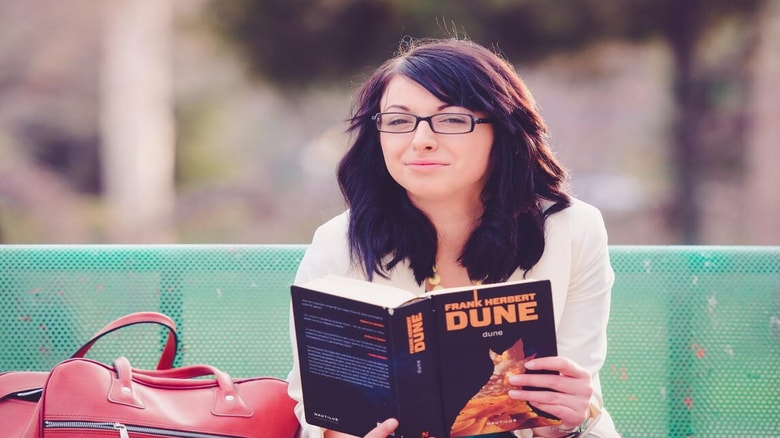 Black hair woman with eyeglass holding a book